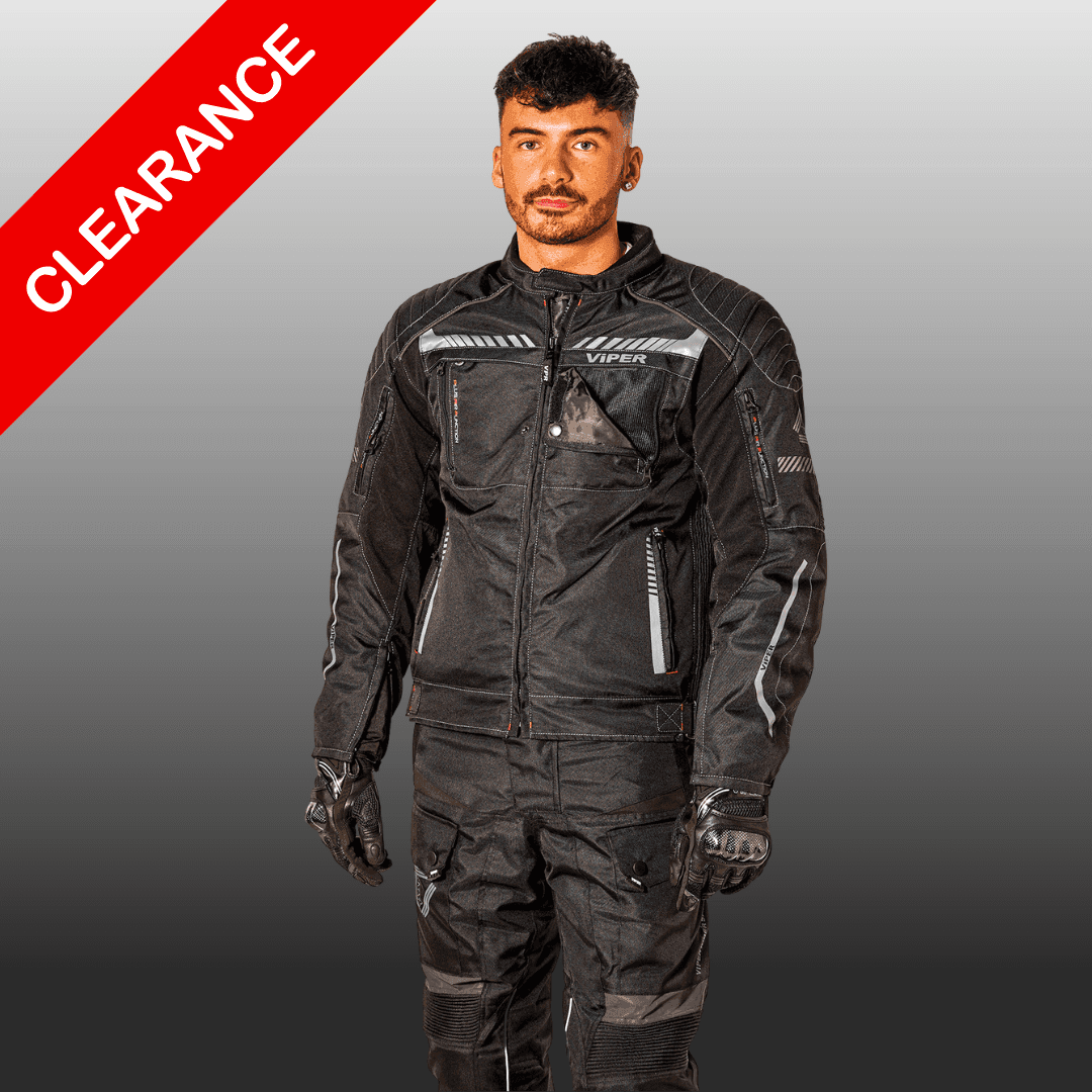 Man wearing black Viper motorcycle gear, standing with a clearance banner in the background.