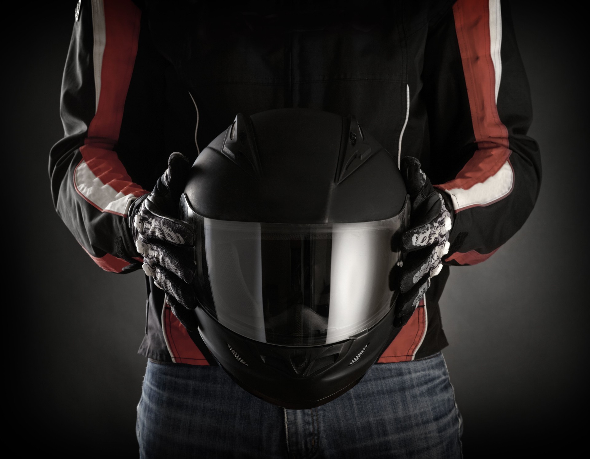 Man holds black motorcycle helmet with visor